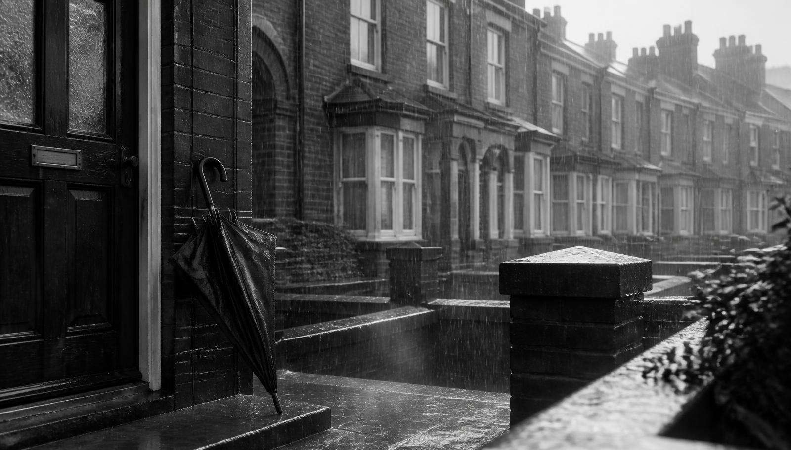 Rain falling on a terraced street with an umbrella resting by a front door