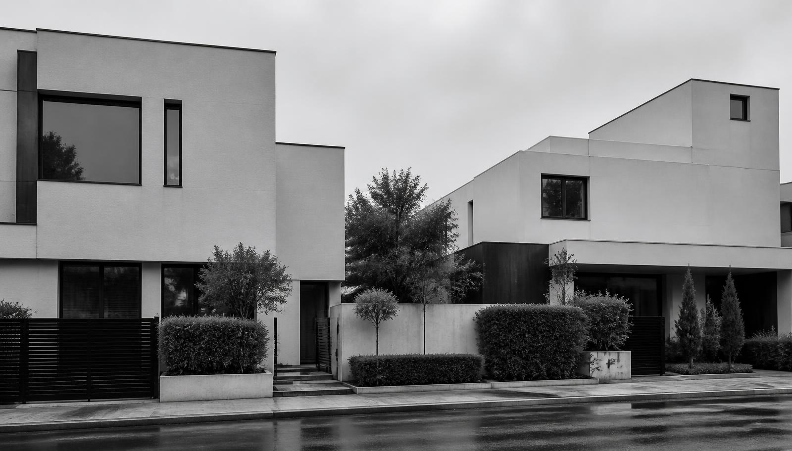 Row of modern residential houses on a wet street under overcast light